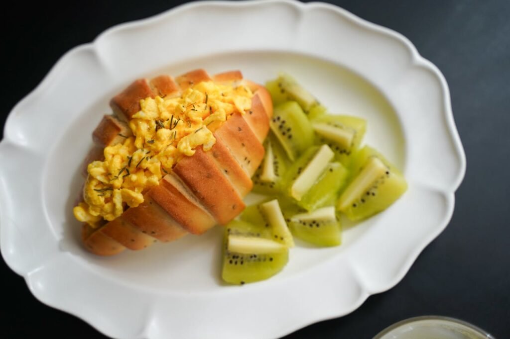 pexels-photo-29616955 Delicious scrambled egg sandwich paired with fresh kiwi slices on a decorative plate.
