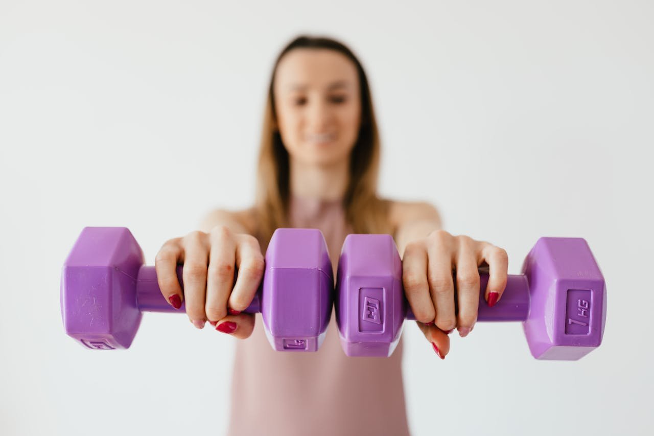 pexels-photo-4498294-1 Defocused content young female doing bicep exercise with dumbbells during functional training in light studio