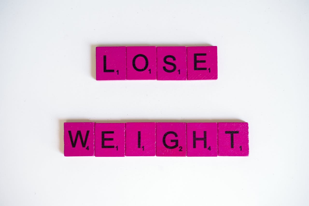 Creative image of the phrase 'Lose Weight' spelled with Scrabble tiles on a white background.